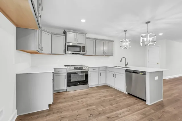 a kitchen with kitchen island granite countertop a stove top oven a sink a counter space and cabinets