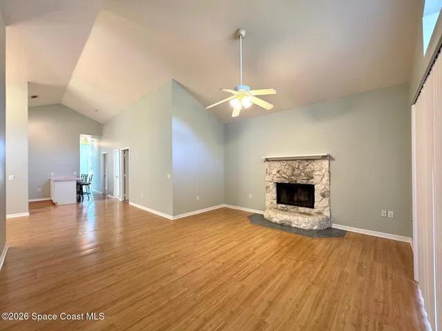 a view of an empty room with wooden floor fireplace and a window