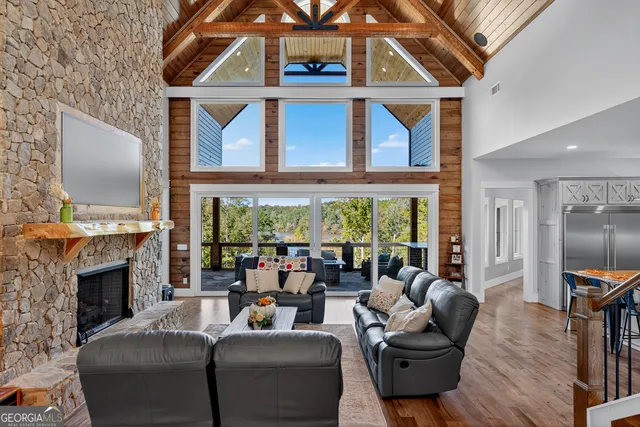 a living room with furniture a fireplace and floor to ceiling windows