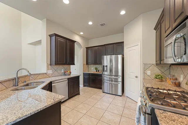 a kitchen with stainless steel appliances granite countertop a sink stove and refrigerator