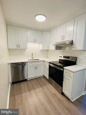 a kitchen with stainless steel appliances granite countertop a stove a sink and white cabinets