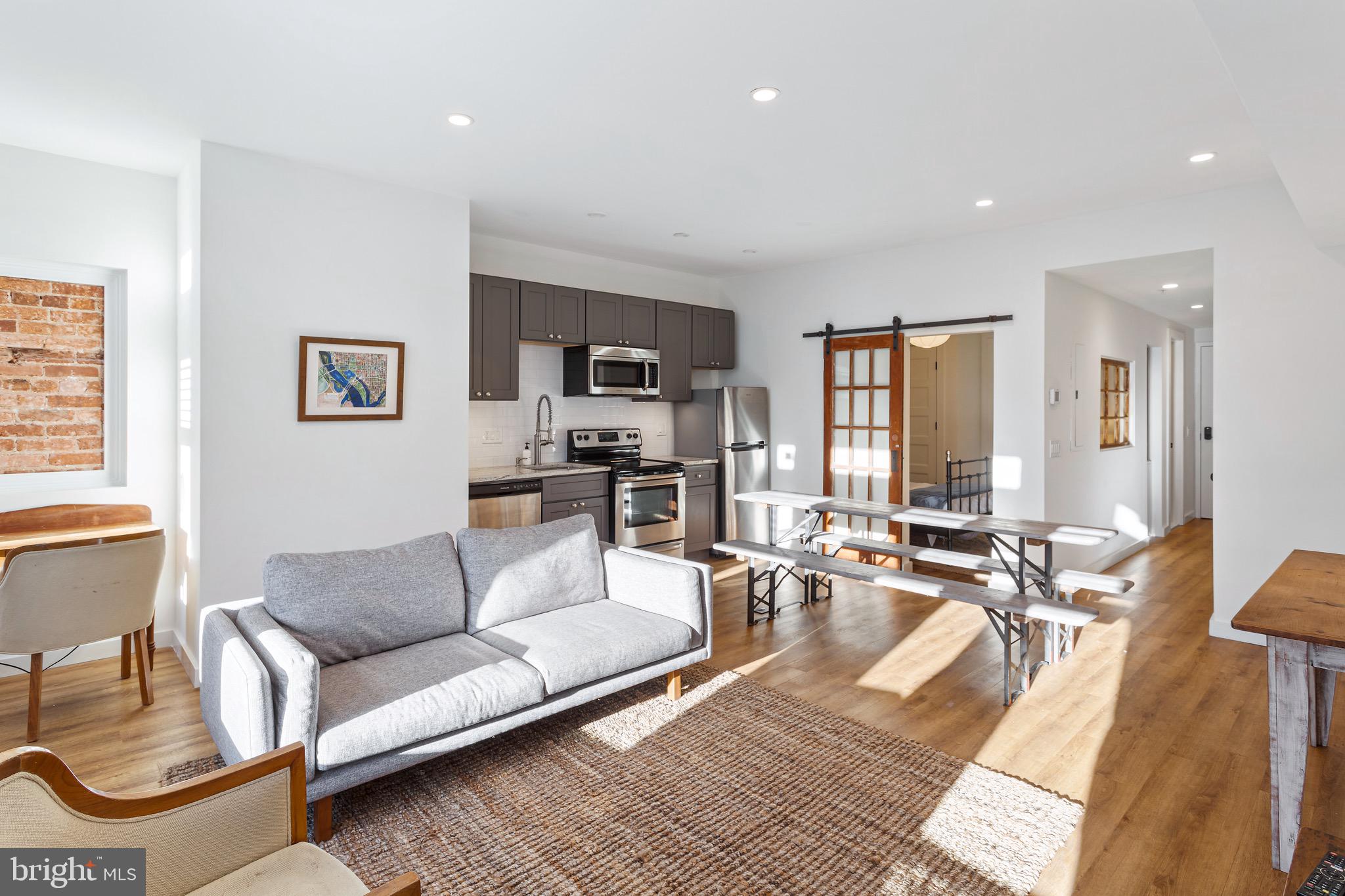 a living room with furniture a rug kitchen view and a large window