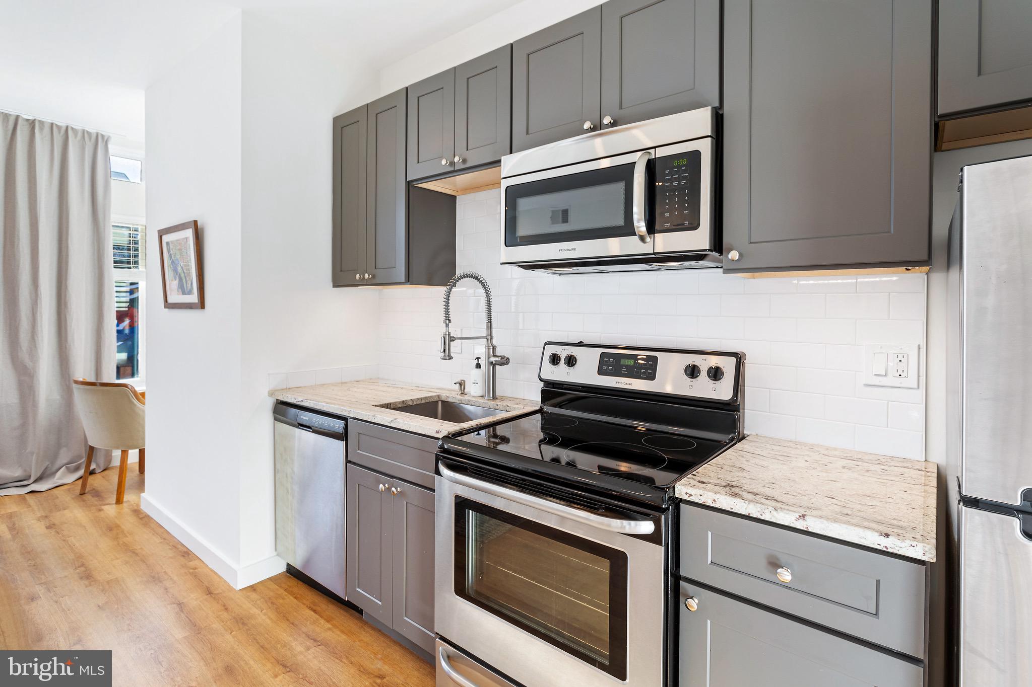 2465 18th Street Northwest, Unit 1 Washington, DC 20009 - Photo 9 of 17 a kitchen with stainless steel appliances granite countertop a stove microwave and sink