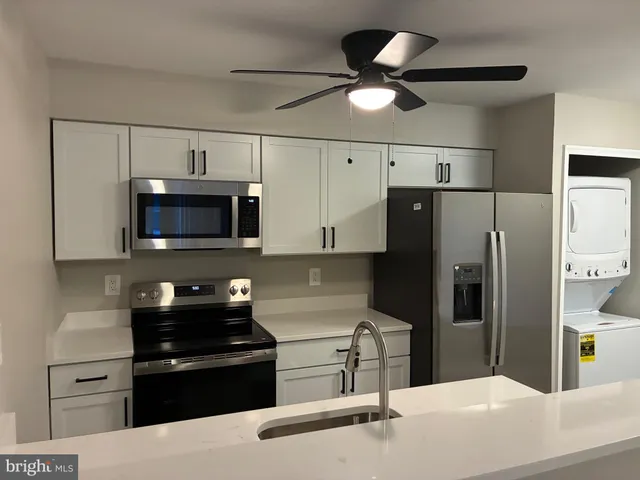 a kitchen with stainless steel appliances kitchen island granite countertop a refrigerator a stove a microwave oven with cabinets