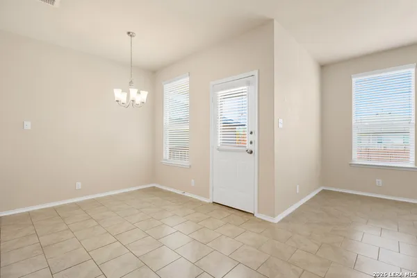an empty room with chandelier fan and windows