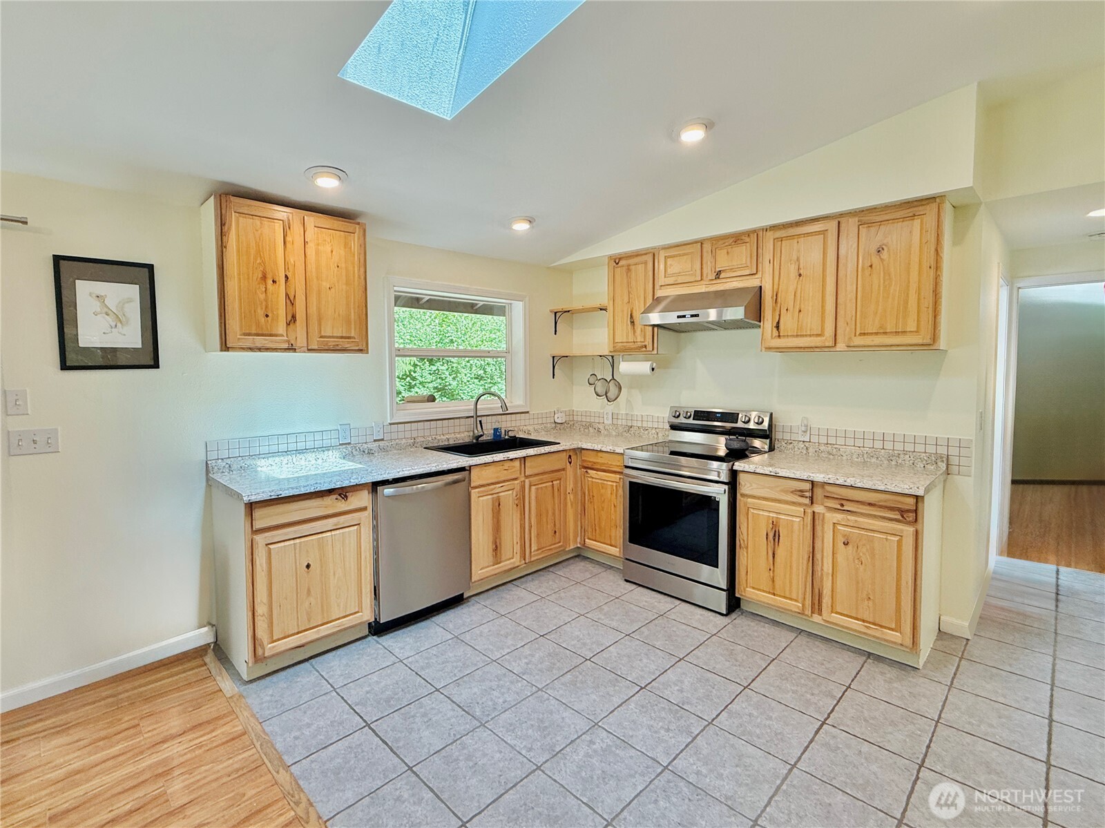 11422 Leschi Circle Anderson Island, WA 98303 - Photo 11 of 40 a kitchen with granite countertop white cabinets a sink a window and stainless steel appliances