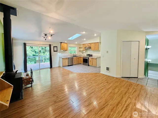 a large kitchen with stainless steel appliances a large counter top a stove a chimney a sink and a large window