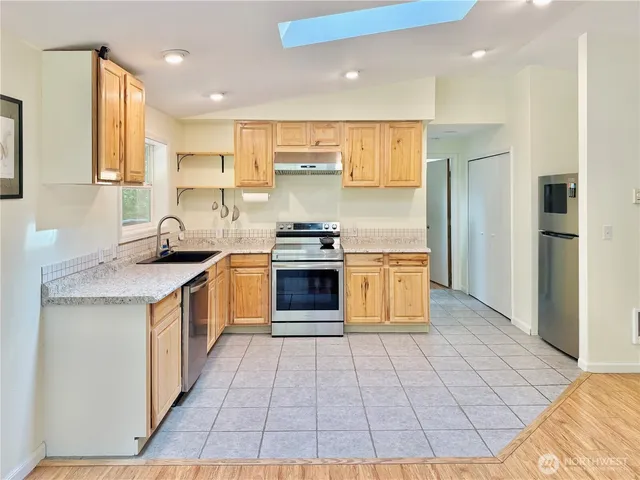 a kitchen with granite countertop white cabinets a sink a window and stainless steel appliances