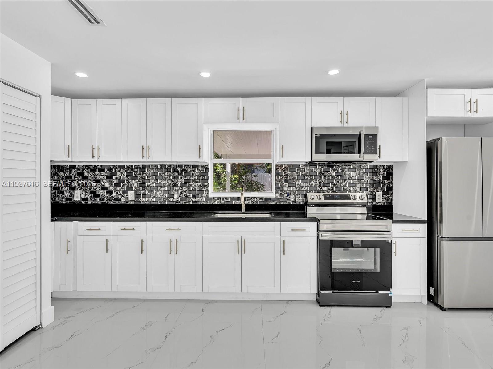 3354 Northwest 50th Street, Unit 3354 Miami, FL 33142 - Photo 7 of 26 a kitchen with stainless steel appliances granite countertop a refrigerator sink stove microwave and cabinets