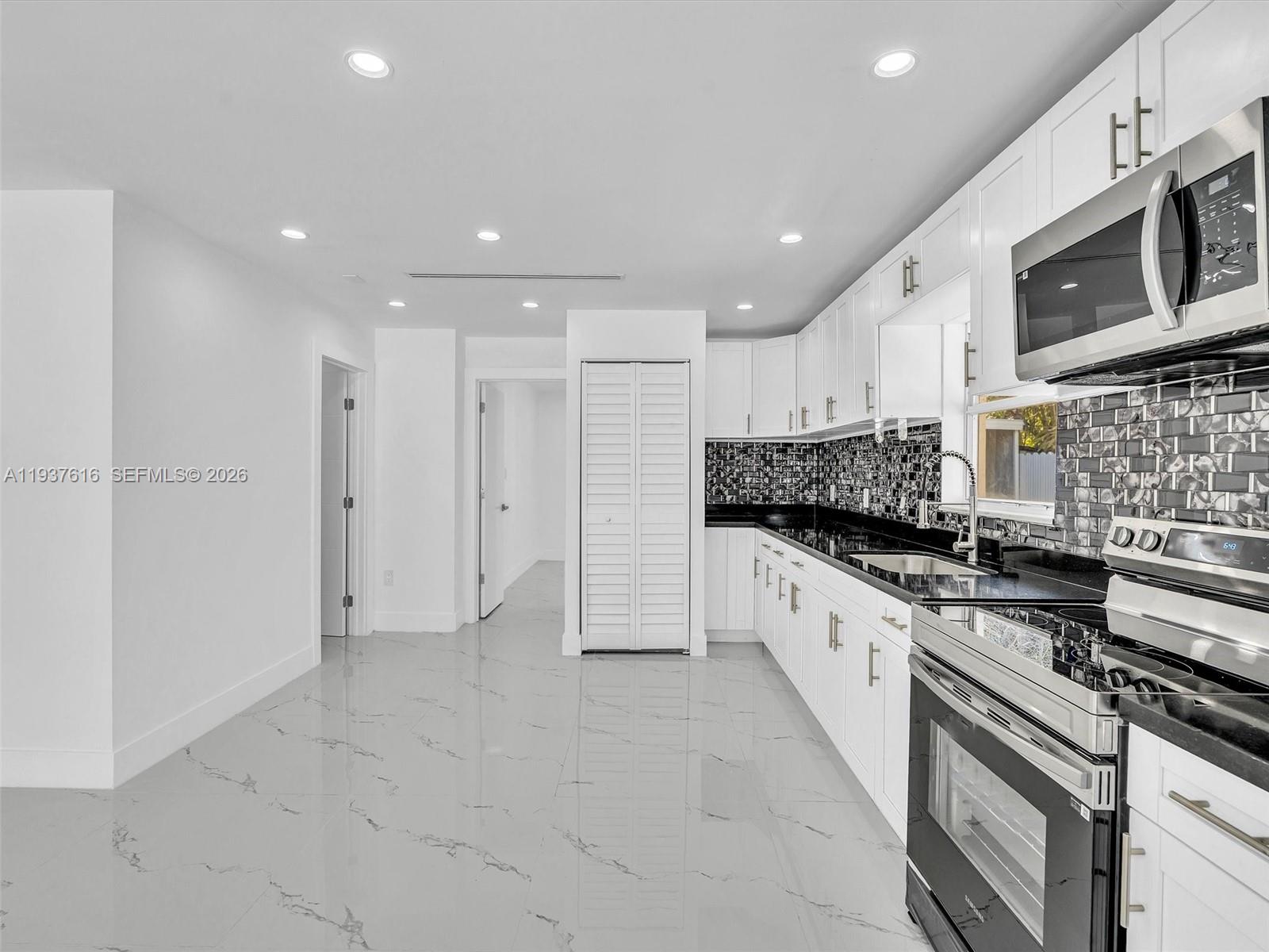 3354 Northwest 50th Street, Unit 3354 Miami, FL 33142 - Photo 8 of 26 a large kitchen with stainless steel appliances granite countertop a stove a sink and a refrigerator