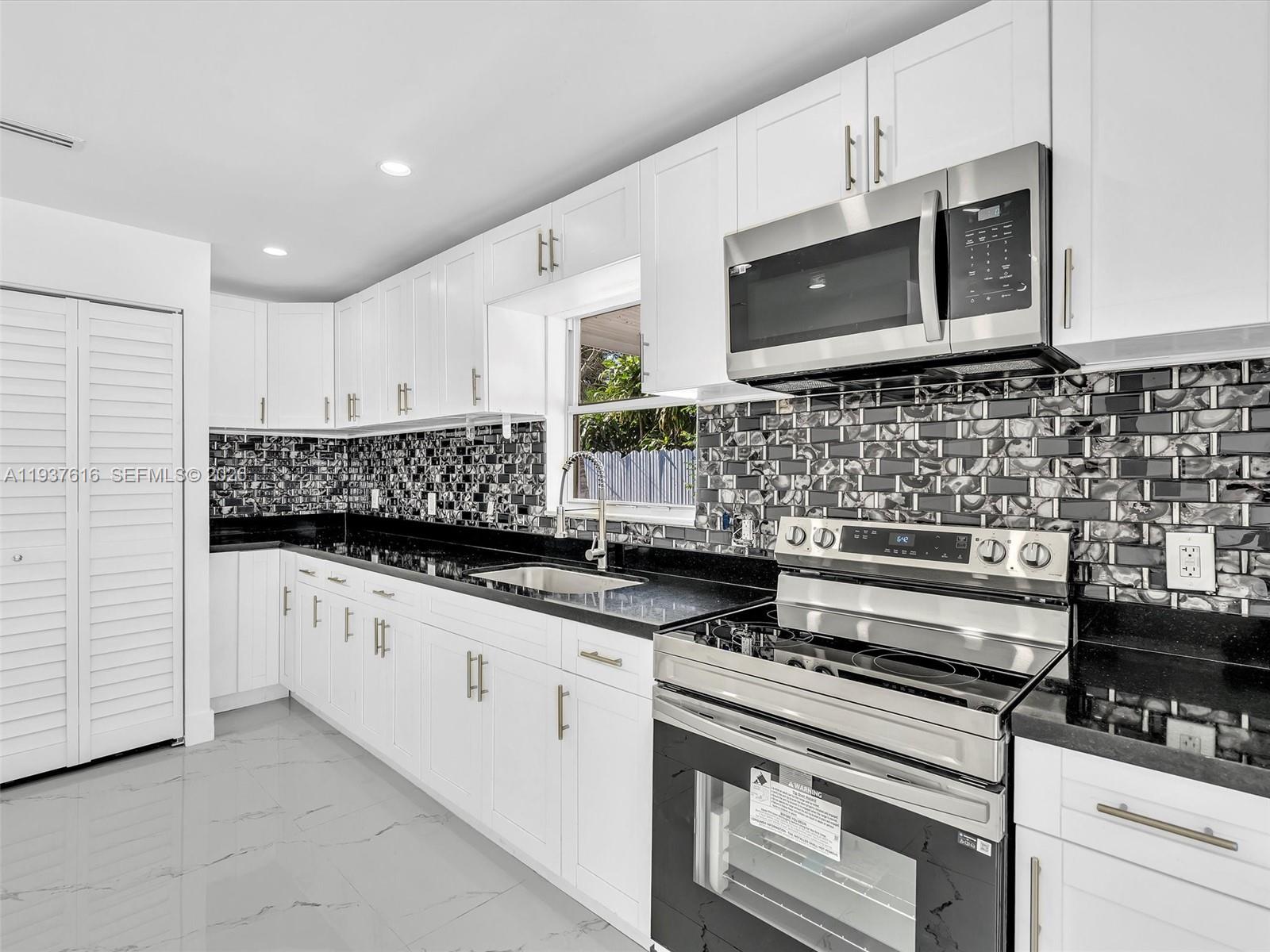 3354 Northwest 50th Street, Unit 3354 Miami, FL 33142 - Photo 9 of 26 a kitchen with stainless steel appliances granite countertop a stove and a microwave