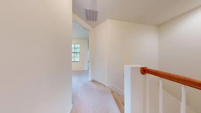 a view of a hallway with closet and bathroom