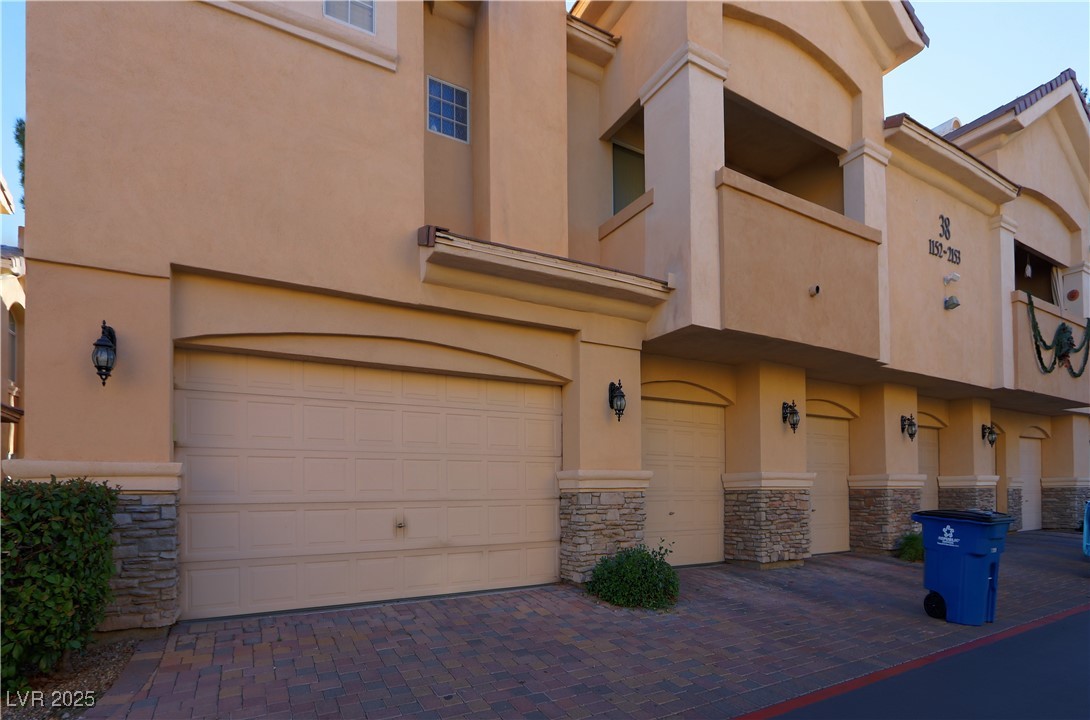 View of property with a garage and decorative driveway