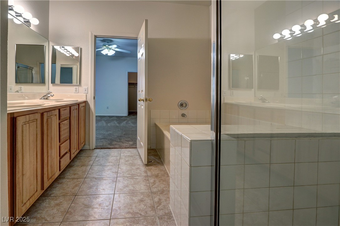 3555 Meridale Drive, Unit 2153 Las Vegas, NV 89147 - Photo 15 of 24 Bathroom featuring light tile patterned flooring, double vanity, a bath, a stall shower, and ceiling fan