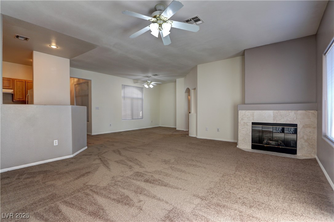 3555 Meridale Drive, Unit 2153 Las Vegas, NV 89147 - Photo 4 of 24 Unfurnished living room with light colored carpet, a tile fireplace, and ceiling fan