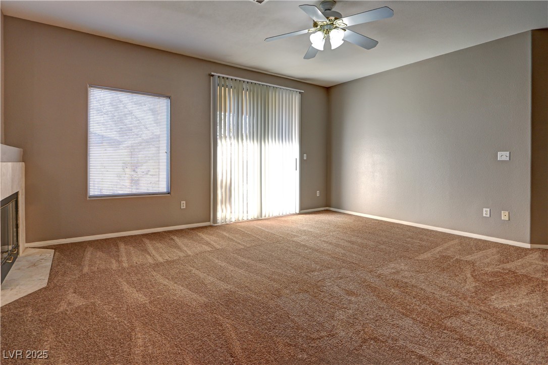 3555 Meridale Drive, Unit 2153 Las Vegas, NV 89147 - Photo 7 of 24 Unfurnished living room featuring a fireplace with flush hearth, carpet, and ceiling fan