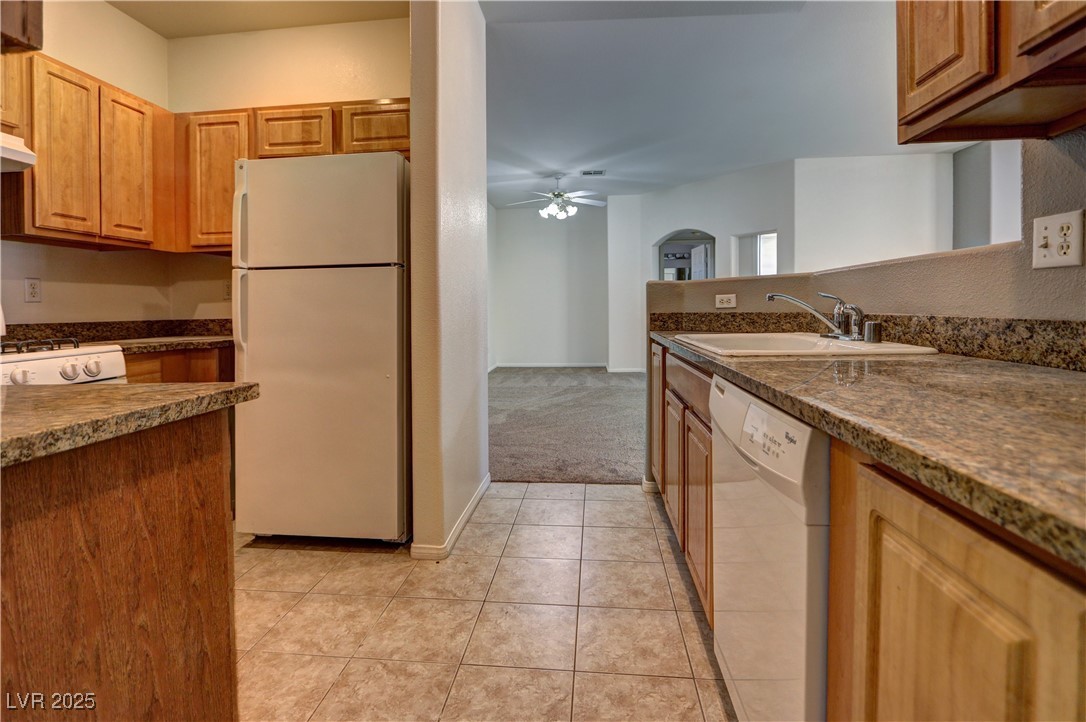 3555 Meridale Drive, Unit 2153 Las Vegas, NV 89147 - Photo 10 of 24 Kitchen with white appliances, ceiling fan, light tile patterned floors, arched walkways, and brown cabinetry