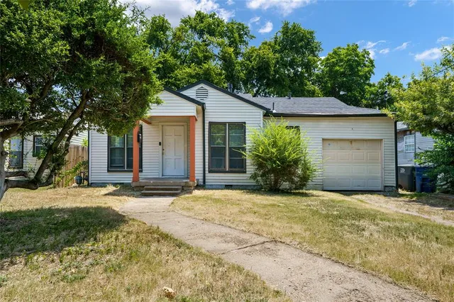 a view of a house with a yard and large tree