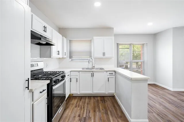 a kitchen with stainless steel appliances a sink dishwasher stove refrigerator and cabinets