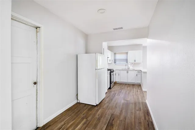 a view of a kitchen with white cabinets and wooden floor