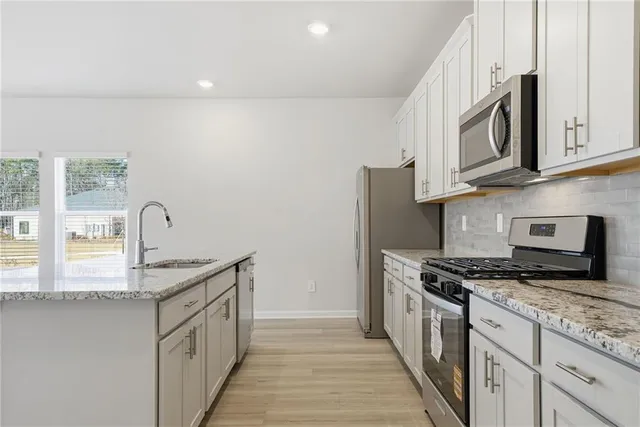a kitchen with granite countertop a sink stainless steel appliances and cabinets