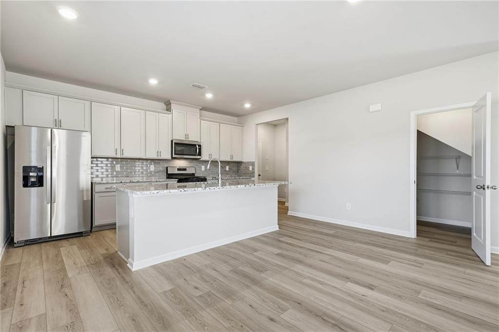 1503 Wild Fox Run Lawrenceville, GA 30045 - Photo 10 of 46 a kitchen with wooden floors white cabinets and stainless steel appliances