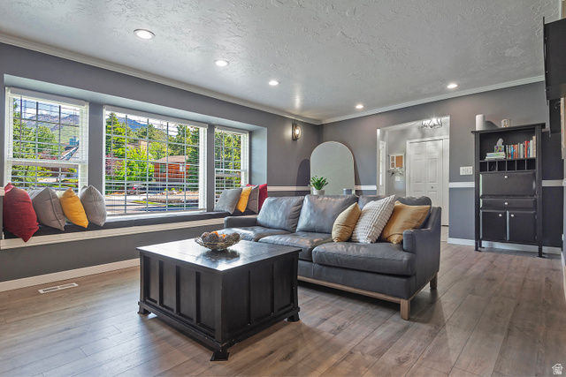 3310 Creek Road Salt Lake City, UT 84121 - Photo 9 of 49 Spacious living area featuring a wide window seat with multiple windows, wood-finish flooring, recessed lighting, crown molding, and a two-tone wall treatment
