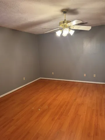 a view of a room with wooden floor and a ceiling fan