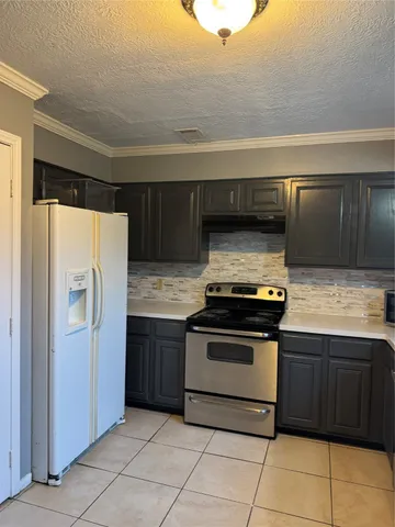 a kitchen with granite countertop a stove and a refrigerator with white cabinets
