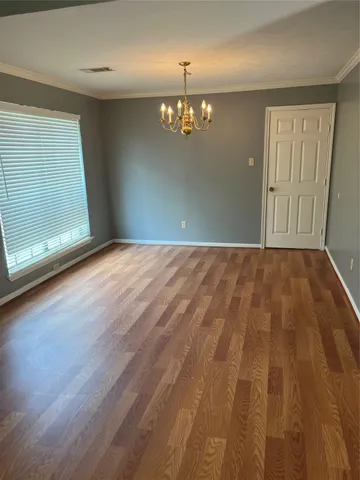 an empty room with wooden floor door and windows