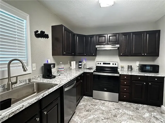 a kitchen with stainless steel appliances granite countertop a sink dishwasher stove and cabinets
