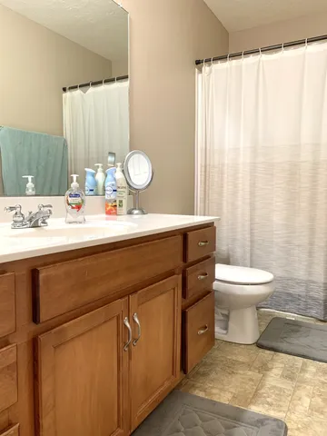 a bathroom with a granite countertop sink toilet a mirror and shower curtain
