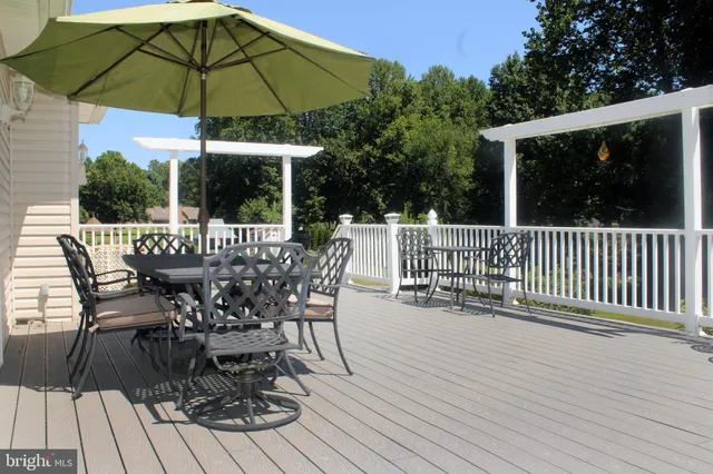 a view of a roof deck with table and chairs under an umbrella with wooden floor and fence