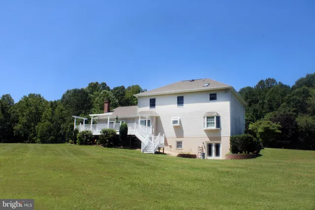 a view of a white house with a big yard and large trees