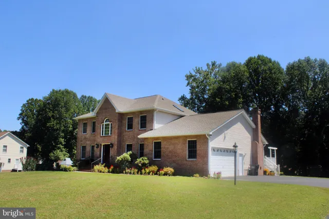a front view of house with yard and trees in the background