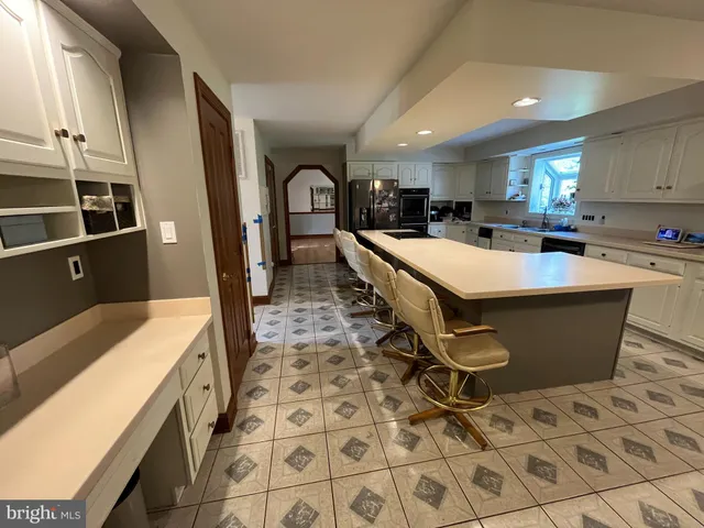 a large kitchen with stainless steel appliances a sink a counter top space and cabinets