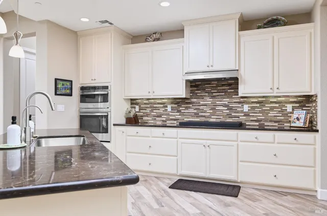 a kitchen with granite countertop a sink a stove and cabinets