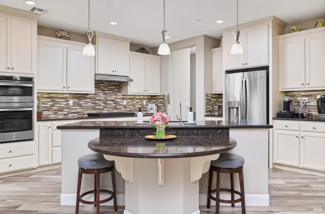 a kitchen with stainless steel appliances granite countertop a table chairs stove microwave and cabinets