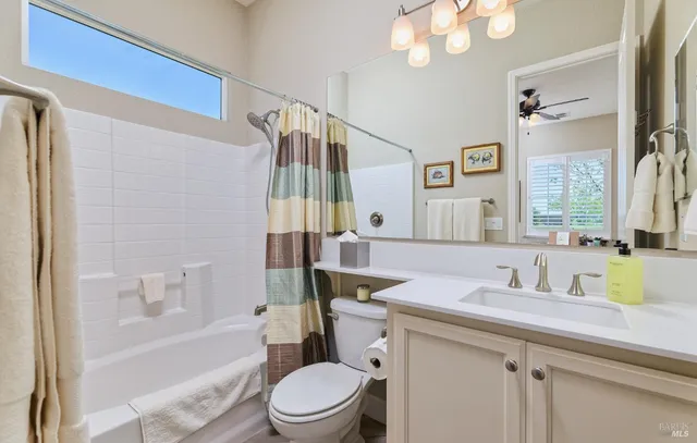 a bathroom with a sink a toilet a mirror a bathtub and shower