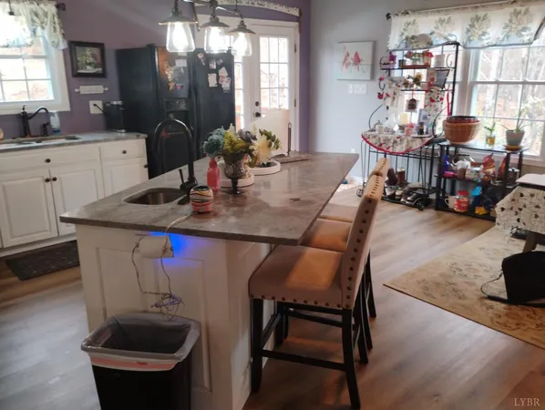 a kitchen with stainless steel appliances a dining table chairs refrigerator and sink
