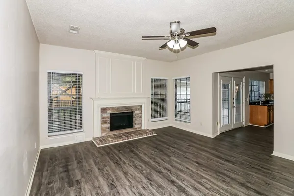 a view of an empty room with wooden floor and a fireplace