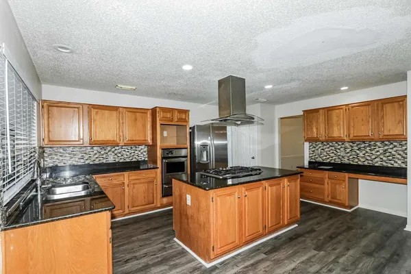 a kitchen with stainless steel appliances granite countertop a stove a sink and a microwave