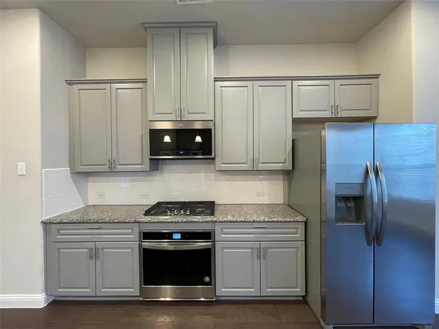 a kitchen with granite countertop white cabinets and stainless steel appliances