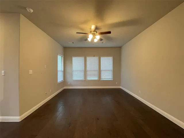 a view of an empty room with chandelier fan and a window