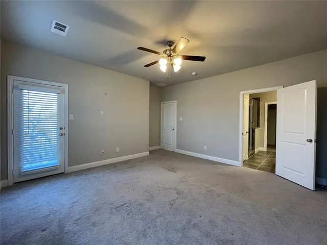 a view of an empty room with a ceiling fan and window