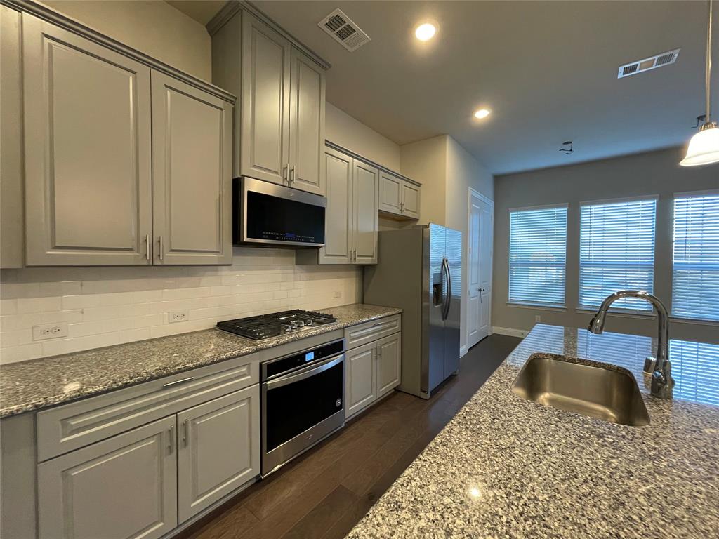 2401 Springhill Avenue Flower Mound, TX 75028 - Photo 7 of 27 a kitchen with a stove a sink and a microwave