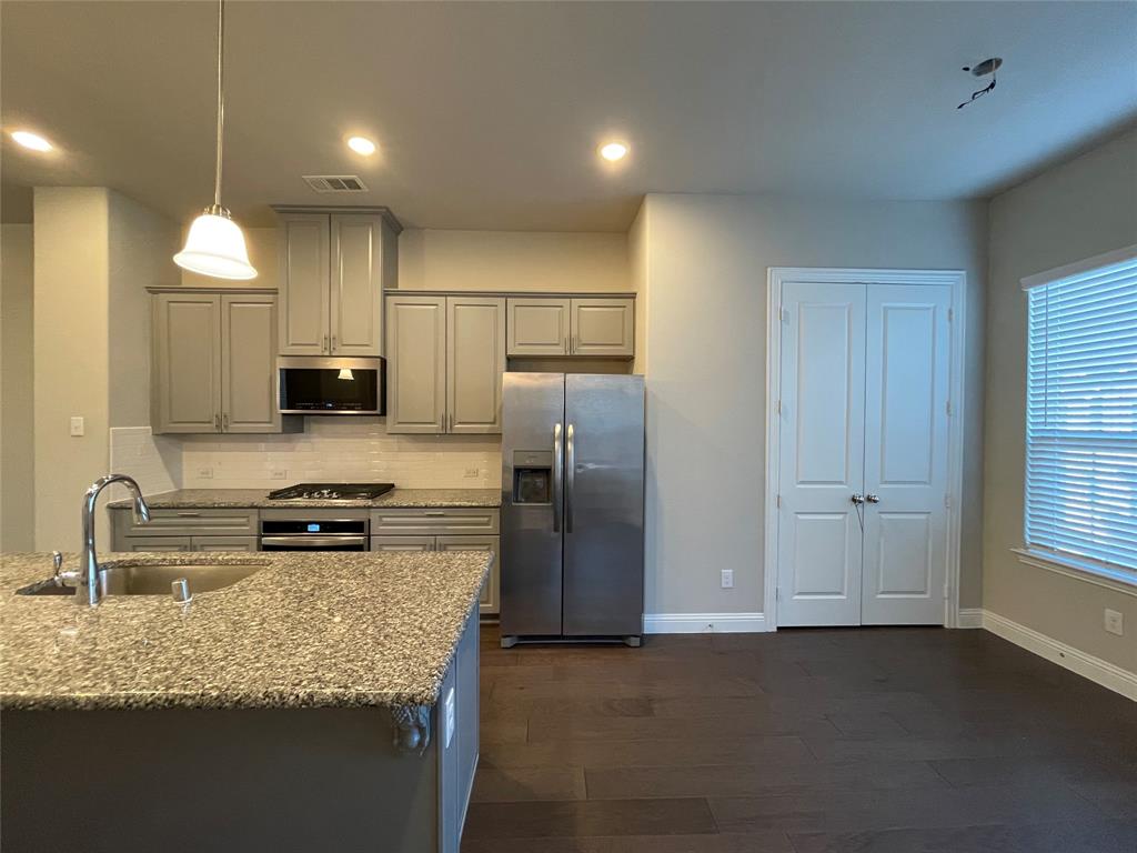 2401 Springhill Avenue Flower Mound, TX 75028 - Photo 10 of 27 a kitchen with kitchen island granite countertop stainless steel appliances a sink stove refrigerator and cabinets