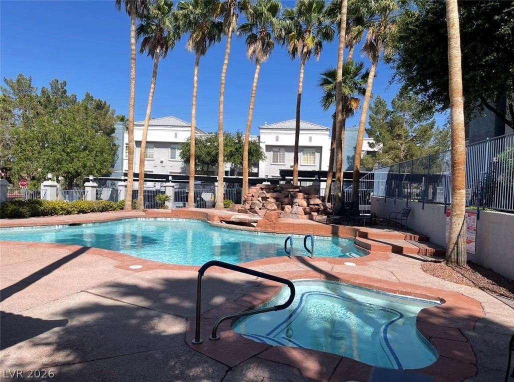 2201 Ramsgate Drive, Unit 915 Henderson, NV 89074 - Photo 9 of 36 Lush palm trees surround a refreshing pool and spa area, creating a serene outdoor oasis.