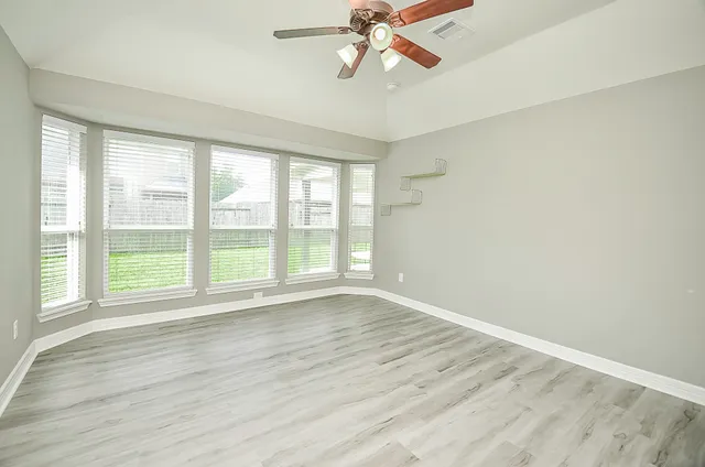 a view of an empty room with wooden floor and a window