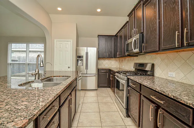 a kitchen with stainless steel appliances granite countertop a sink a stove and a refrigerator